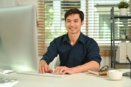 Virtual assistant smiling at camera in front of computer screen